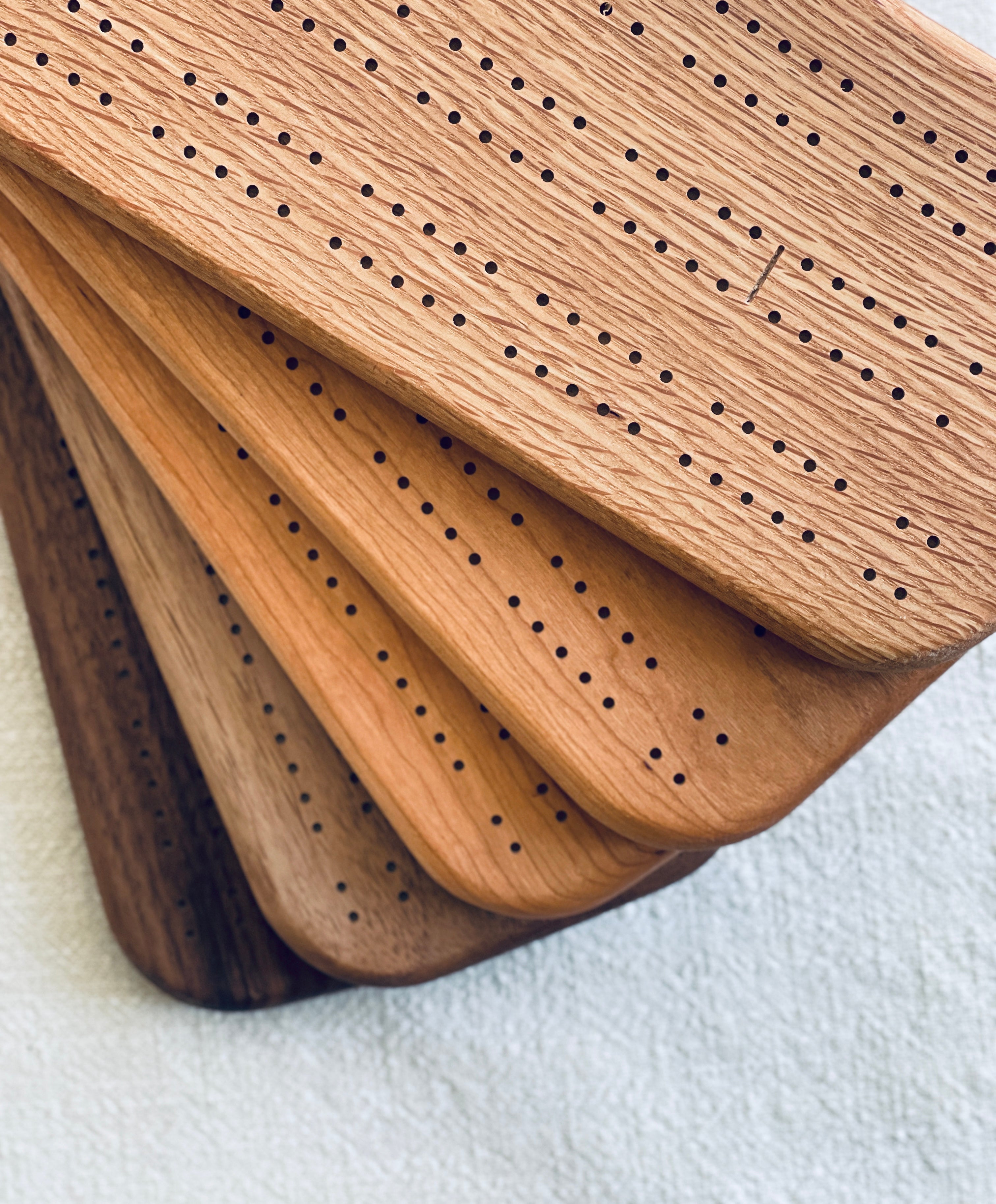 Stack of wooden cribbage boards made from walnut, cherry, and white oak.
